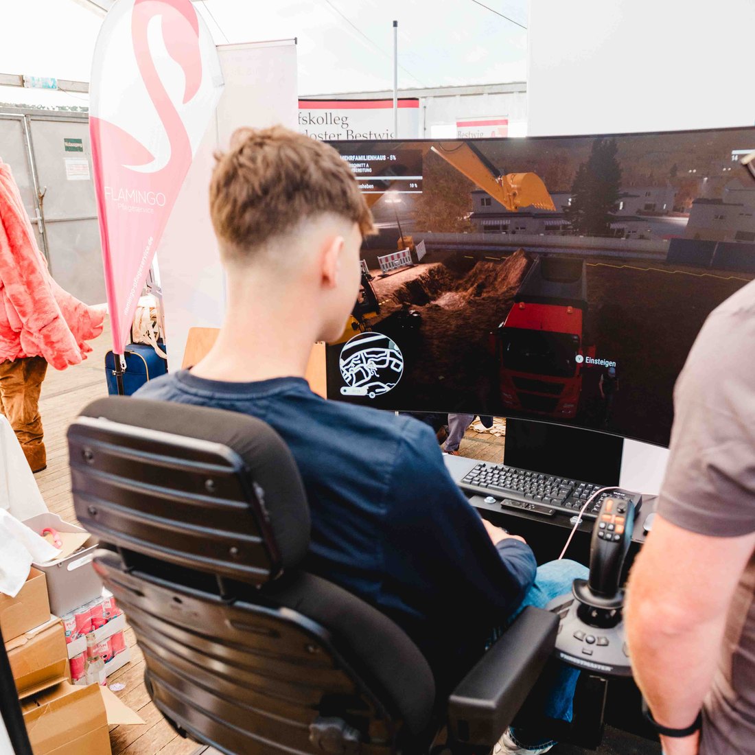 Jugendlicher steuert den Baggersimulator am Stand der Redeker Tiefbau GmbH