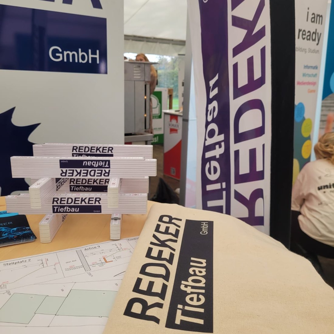 Baustellenpläne und Give-aways der Redeker Tiefbau GmbH auf dem Messetisch