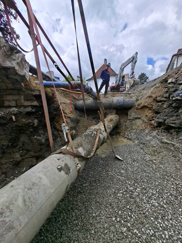 Bauarbeiter in der Rohrgrabenbaustelle neben verlegten Versorgungsleitungen