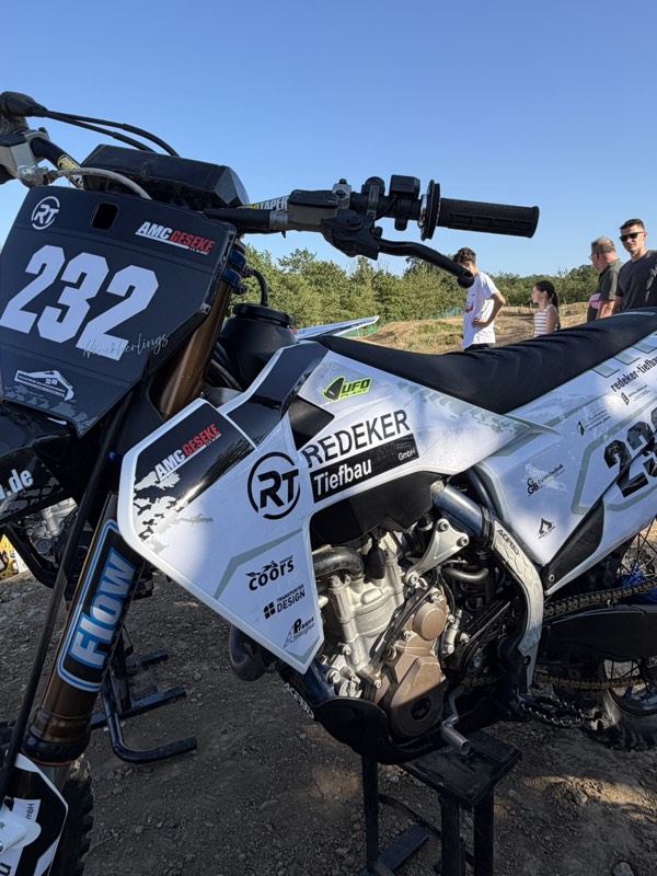 Vereinsmitglied des AMC Geseke sitzt lächelnd auf seinem Redeker-Tiefbau-gebrandeten Motocross-Motorrad