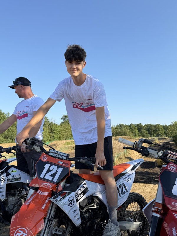 Motocross-Motorrad Nummer 84 im Redeker-Tiefbau-Design vor einem Baufahrzeug