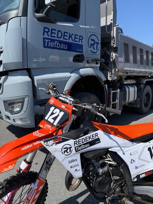 Redeker-Tiefbau-Lkw und Motocross-Motorrad des AMC Geseke nebeneinander