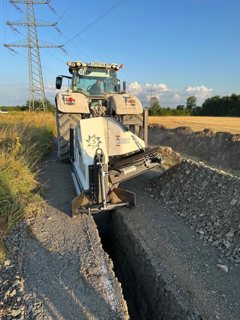 Grabenfräse beim Herstellen eines Leitungsgrabens unter einer Hochspannungstrasse