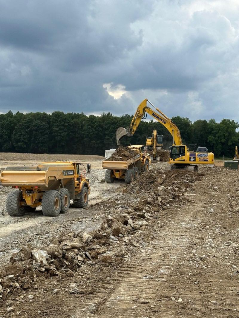 Kettenbagger und Muldenkipper beim Großerdbau auf freiem Feld