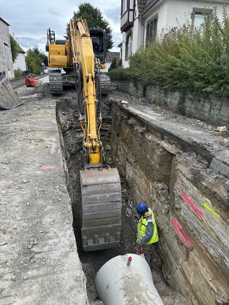 Kettenbagger hebt einen verbauten Rohrgraben in einer Ortsdurchfahrt aus