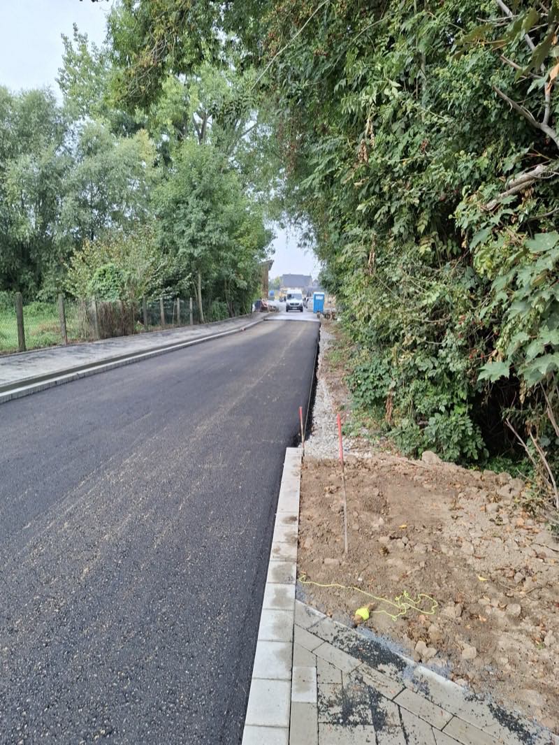 Frisch eingebaute Asphaltdecke mit gesetztem Bordstein an einer Anliegerstraße
