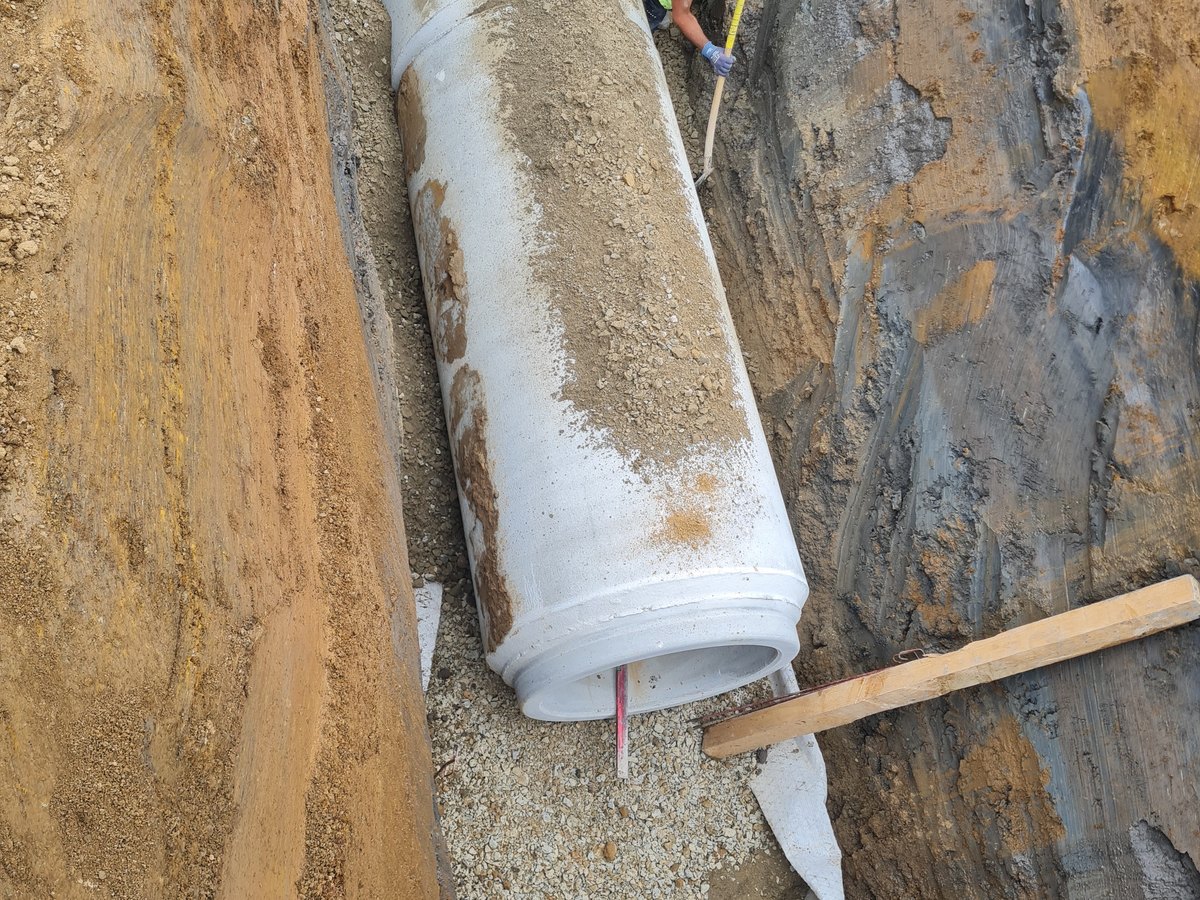 Kanalbauer am verlegten Betonrohr im Rohrgraben