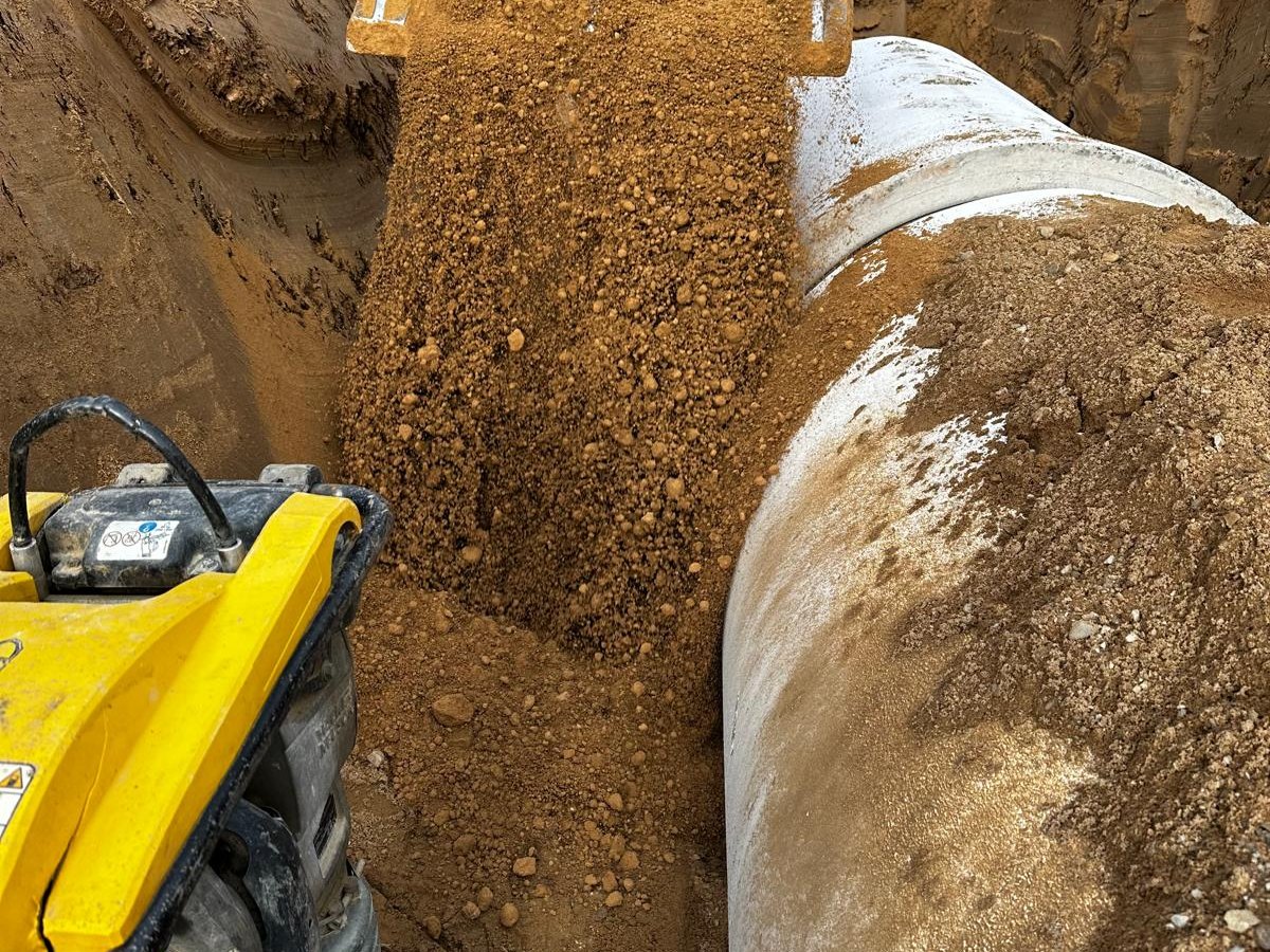 Verdichten der Verfüllung neben dem verlegten Betonrohr