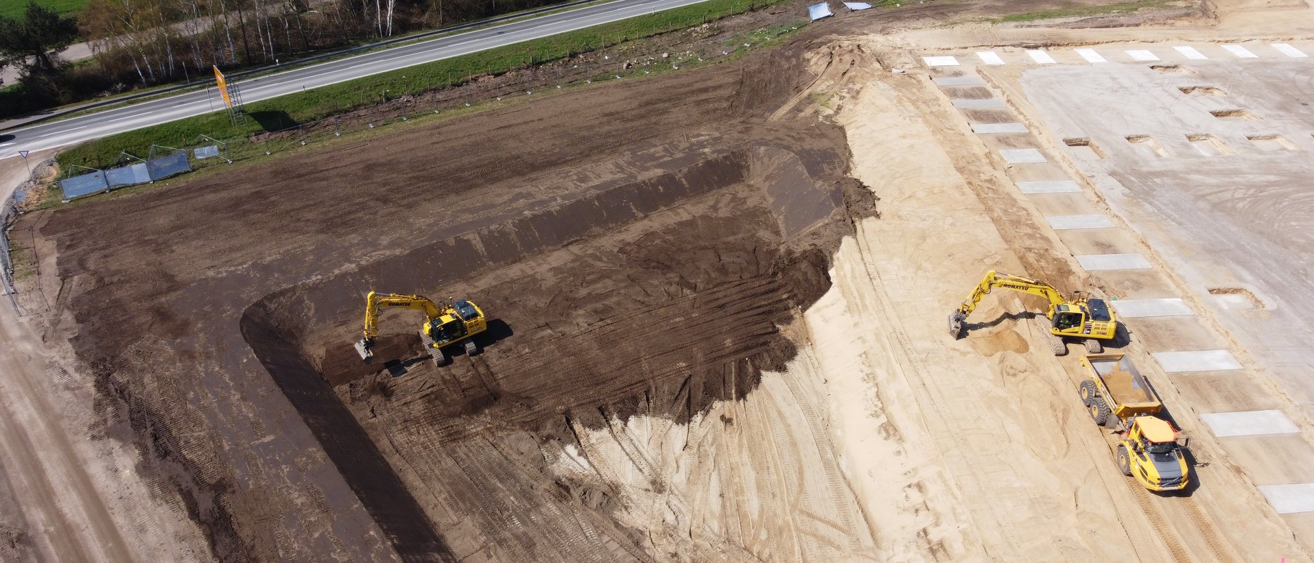 Luftbild des Erdaushubs mit zwei Baggern und Dumper